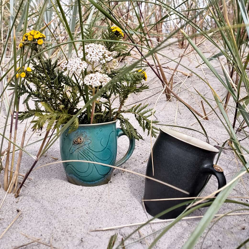 Töpferei Stock Zwei Keramikbecker im Sand. Drumherum Schilf.