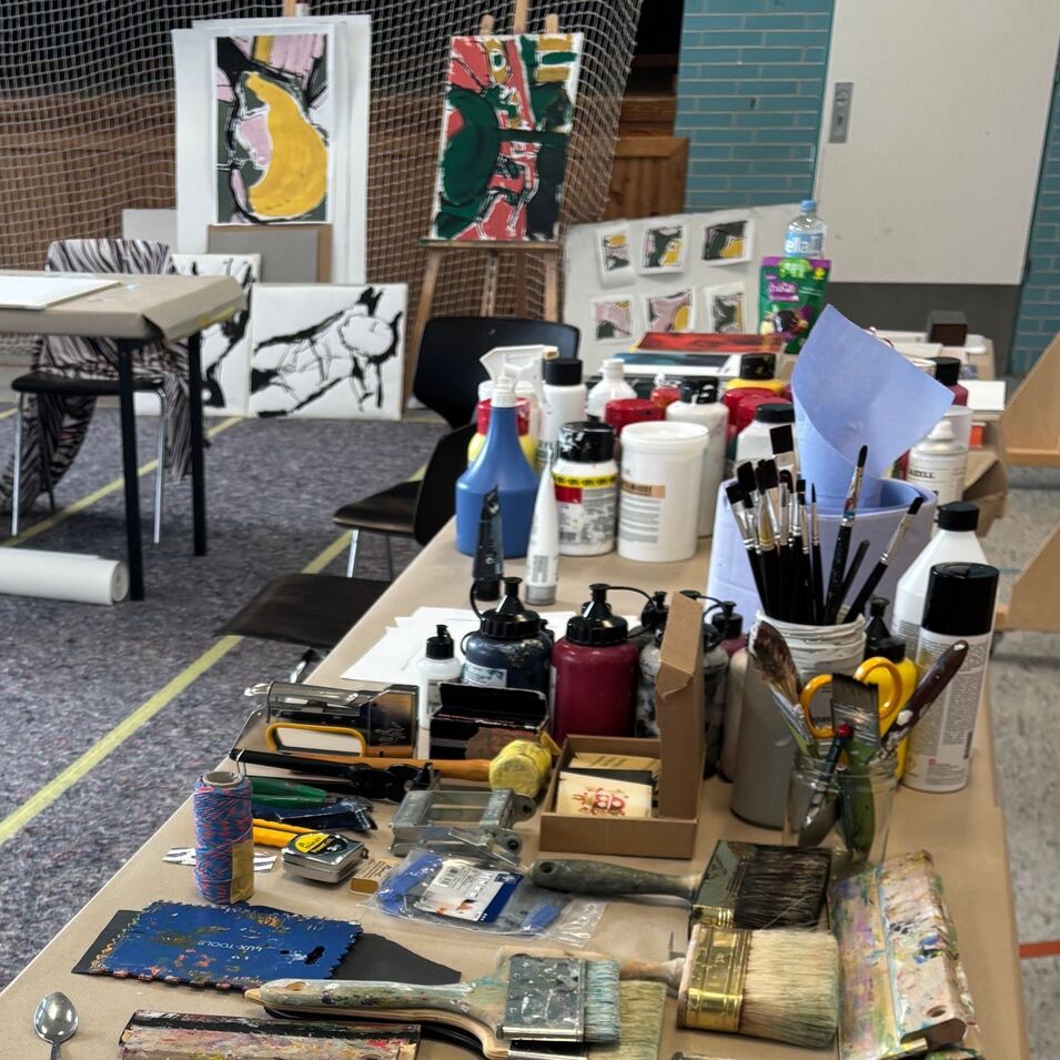 Einblick ins Atelier mit abstrakten Malereien im Hintergrund.