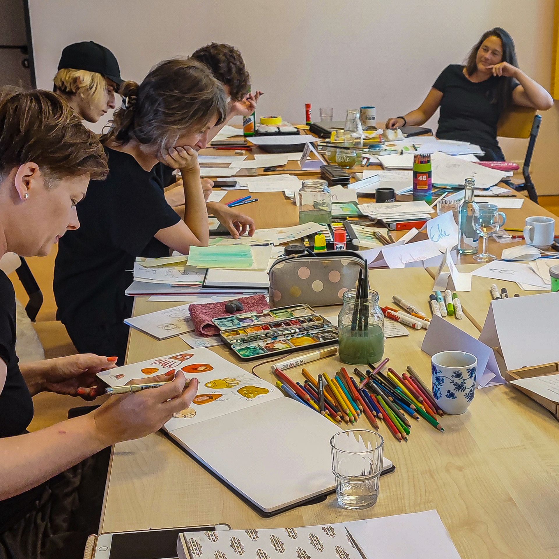 Das Bild zeigt Menschen am Tisch im Kurs Illustration darunter auch Franziska Ludwig
