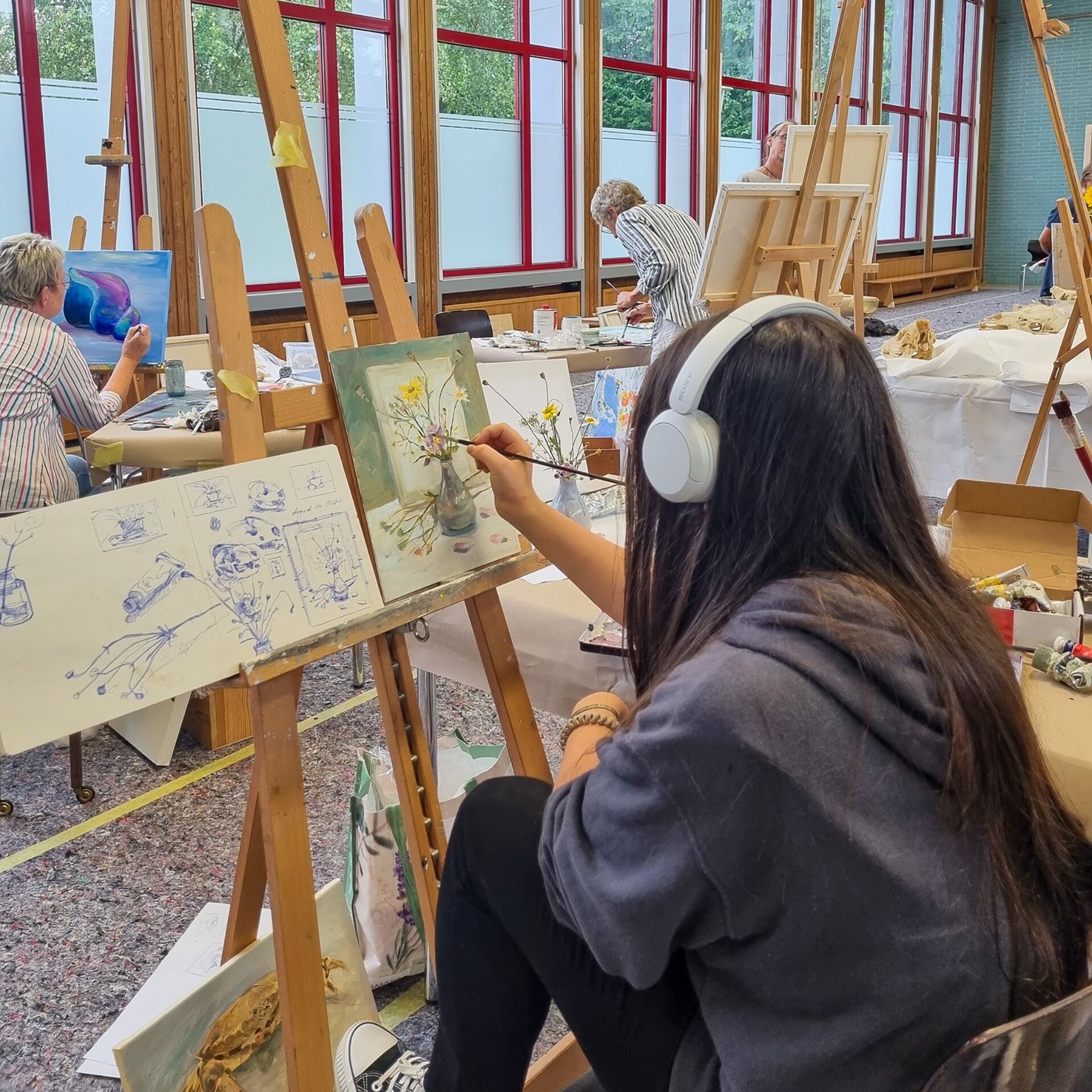 Ein Mädchen malt in einem Atelier an einem Stillleben.