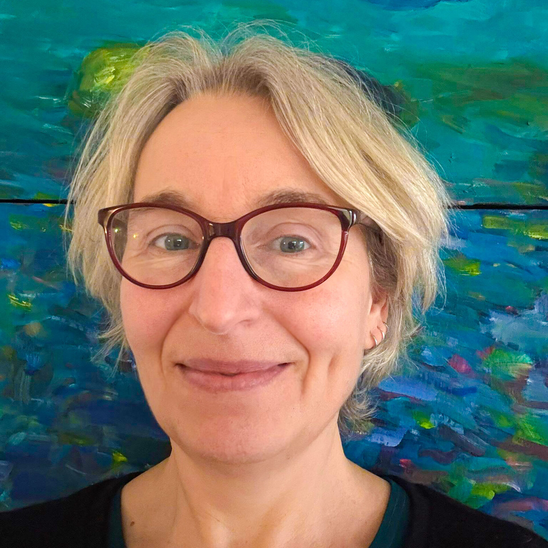Dr. Christina Kohla Dr. Christina Kohla im Porträt. Sie trägt kurze blonde Haare und eine rote Brille.