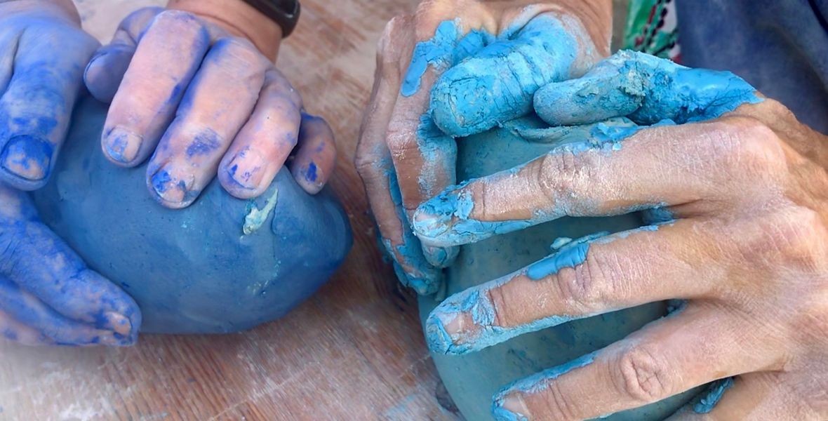 Das Foto zeigt Hände mit blauem, farbigen Ton.