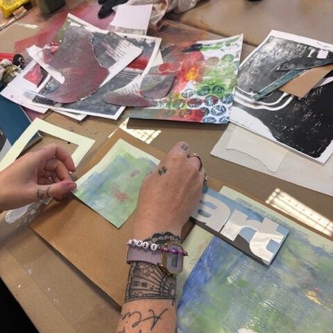 Eine Hand ist zu sehen, die mit Druckerzeugnissen eine Collage enstehen lässt.
