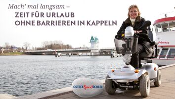 Ein Plakat einer gebehinderten Person, die sich am Hafen befindet. Auf dem Plakat steht der Text "Mach ma' langsam – Zeit für Urlaub ohne Barrieren in Kappeln."