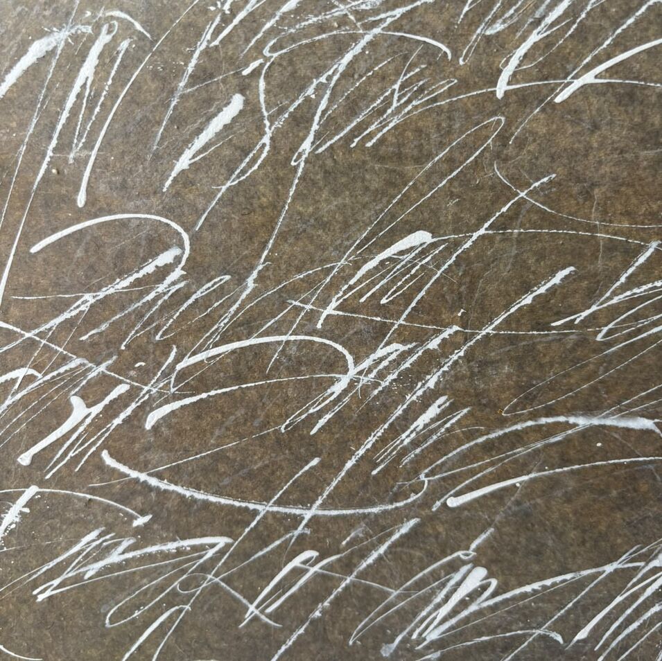 Jasna Wittmann Weiße Kalligrafie auf braunem Hintergrund.