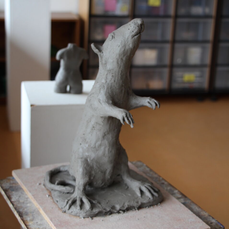 eine in Ton modellierte Ratte steht auf ihren Hinterbeinen und reckt den Kopf nach oben