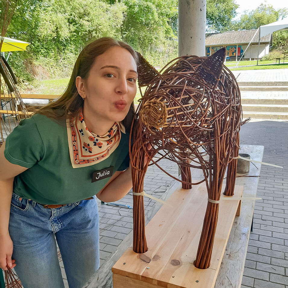 Ein Mädchen mit einem Schwein aus Weidengeflecht.