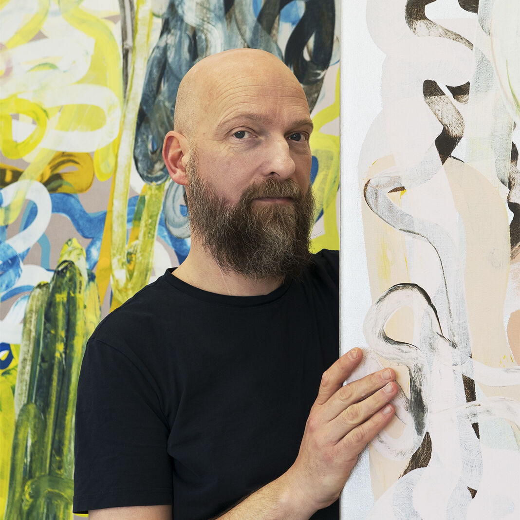 Martin Scholten Martin Scholten im Porträt. Er steht versteckt zwischen seinen Werken.