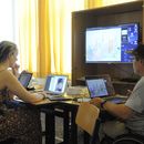 Das Bild zeigt zwei Leute vor ihren Computern