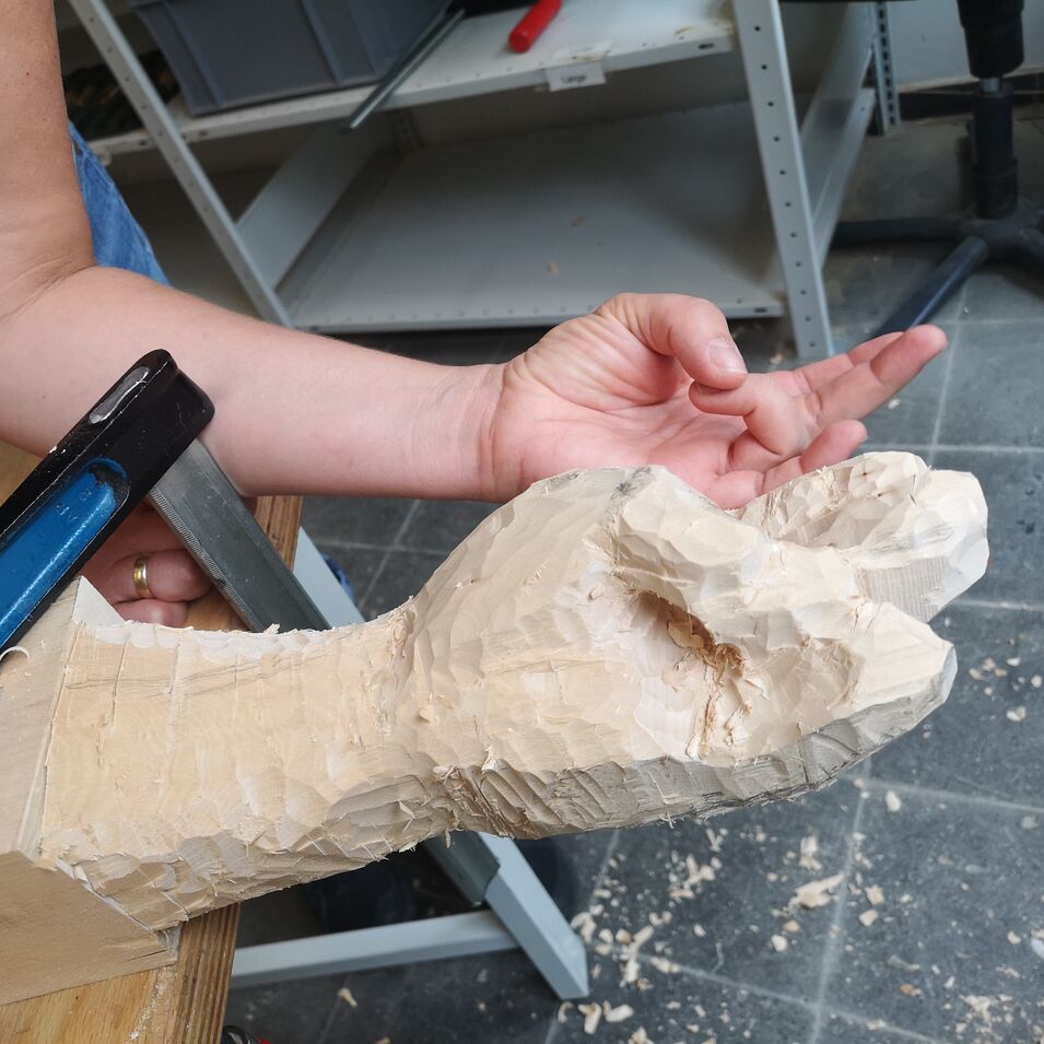 Eine Hand wird in Holz geschnitzt. Hand