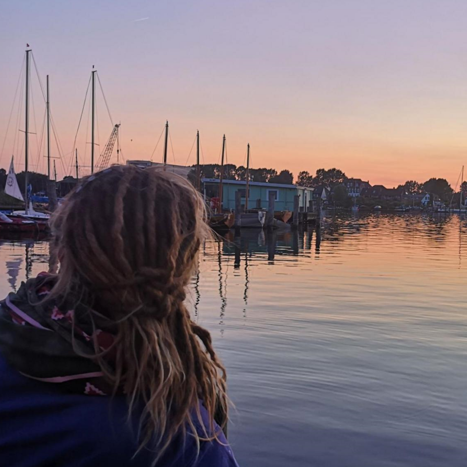 Das Foto zeigt einen Menschen, der die Abendstimmung an der Schlei genießt.