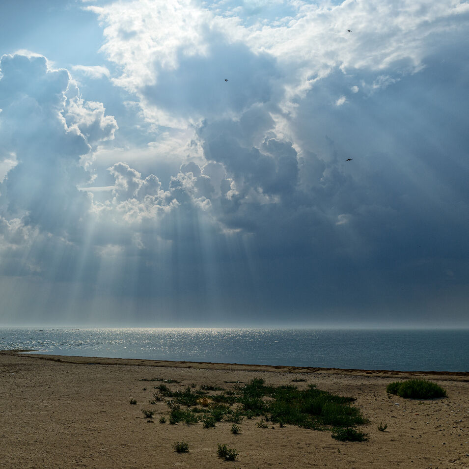 Diese Fotografie zeigt einen Wolkenhimmel mit Sonnenstrahlen.
