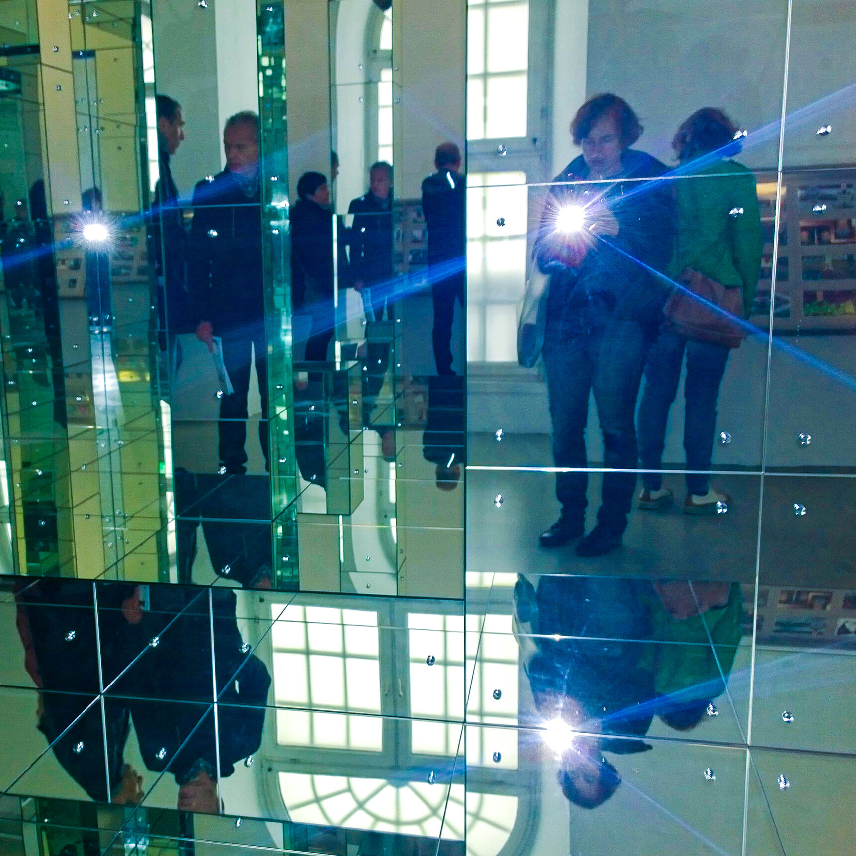 Menschen in einem Spiegelsaal.